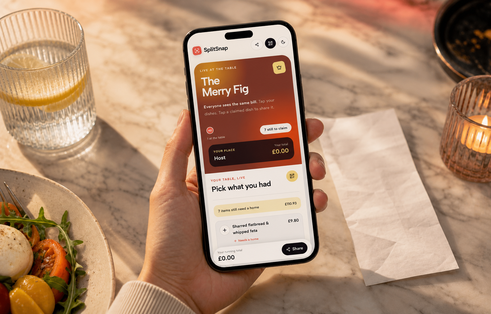 A hand holding a phone showing SplitSnap beside a restaurant receipt